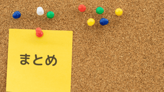 茶色のコルクボードにカラフルなピンが刺さっている画像。赤いピンで留められた黄色い正方形の紙には、黒い文字で”まとめ”と書かれている。